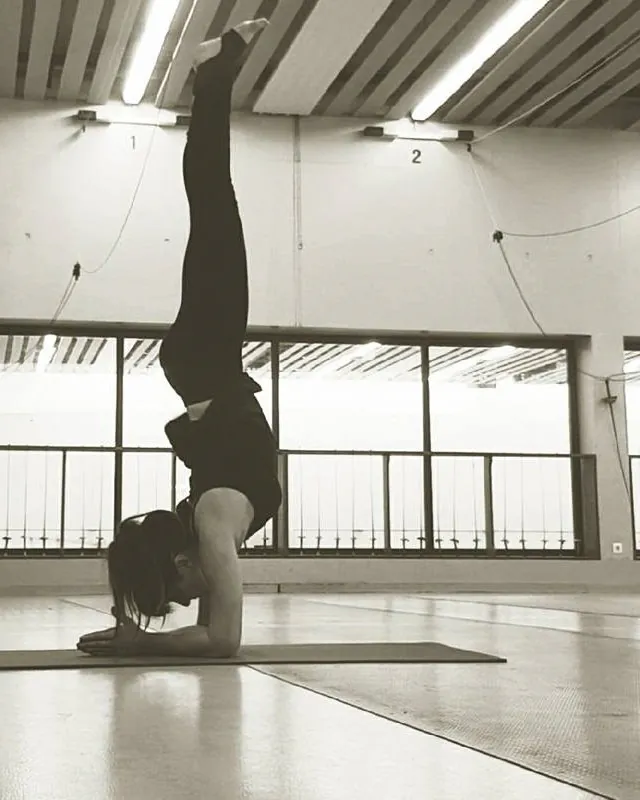 Helena Ona en équilibre sur les avant-bras, jambes à la verticale, dans une salle de pratique